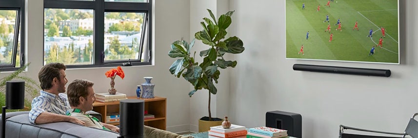 Een zwarte muurbeugel van Sonos voor de Sonos Arc Ultra hangend aan de muur onder de televisie. Een zwarte muurbeugel van Sonos voor de Sonos Arc Ultra hangend aan de muur onder de televisie.