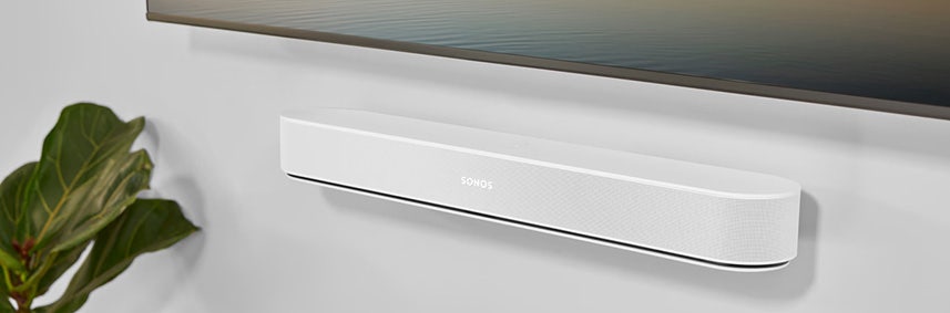 Een witte muurbeugel van Sonos voor de Sonos Beam hangend aan de muur onder de televisie. Een witte muurbeugel van Sonos voor de Sonos Beam hangend aan de muur onder de televisie.