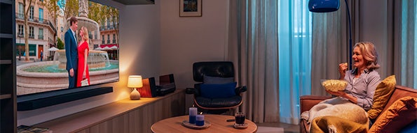 Vrouw zit op de bank televisie te kijken.