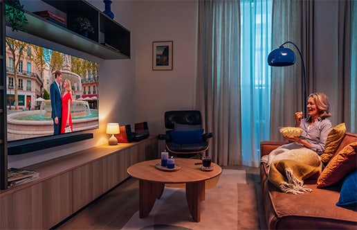 Vrouw zit op de bank televisie te kijken.