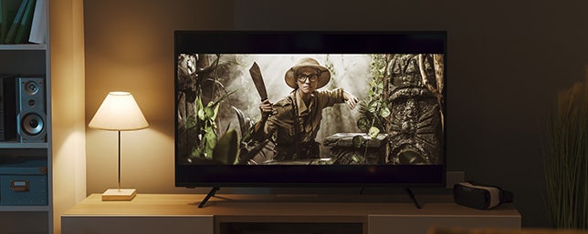 Televisie in de woonkamer, waar een actiefilm in de jungle op te zien is.