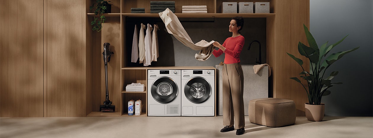 Vrouw doet de was met een wasmachine en droger van Miele. Vrouw doet de was met een wasmachine en droger van Miele.